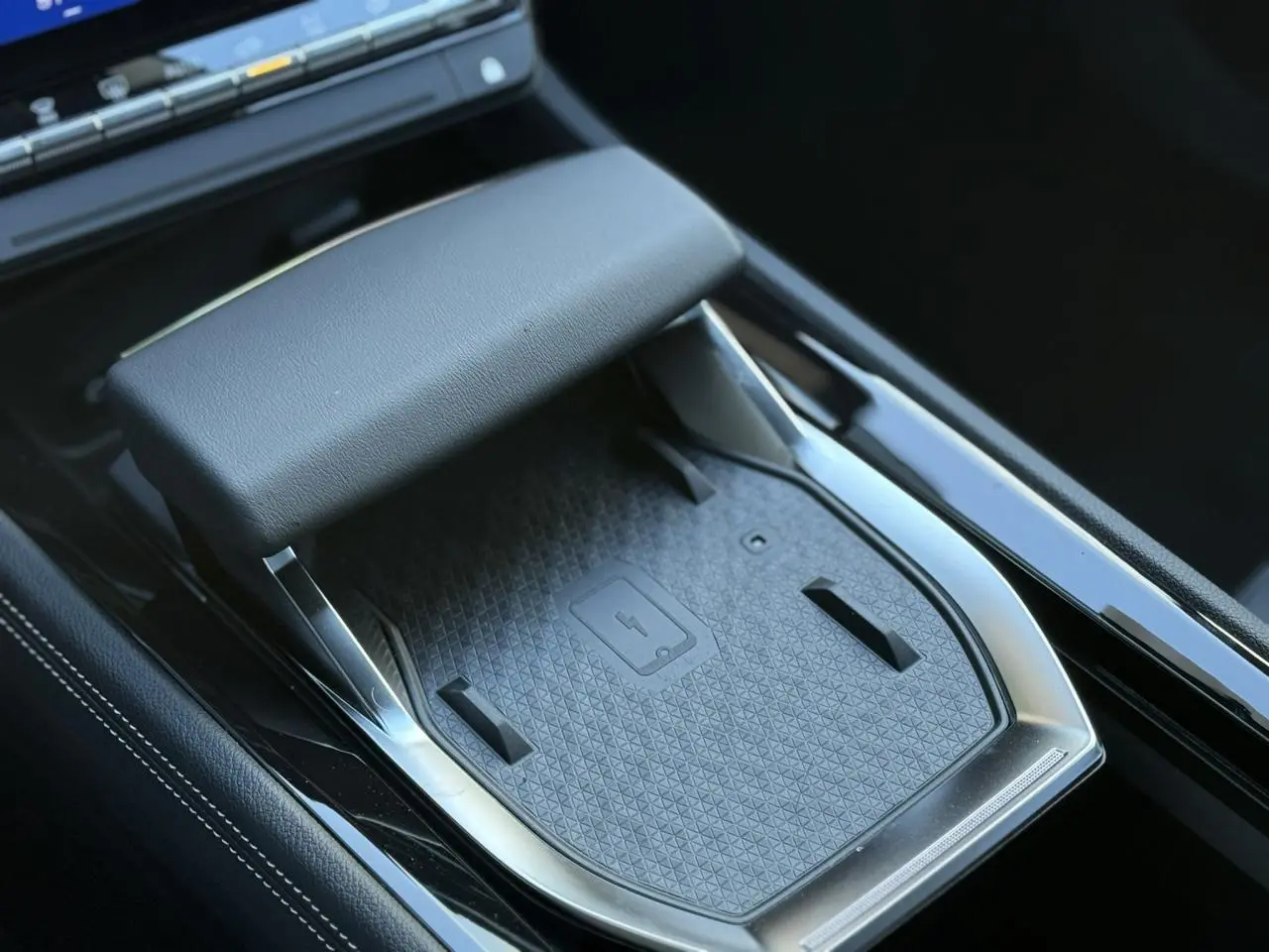 Gros plan sur la console centrale noire du Renault Espace VI 6 E-Tech avec chargeur smartphone à induction et accoudoir.
