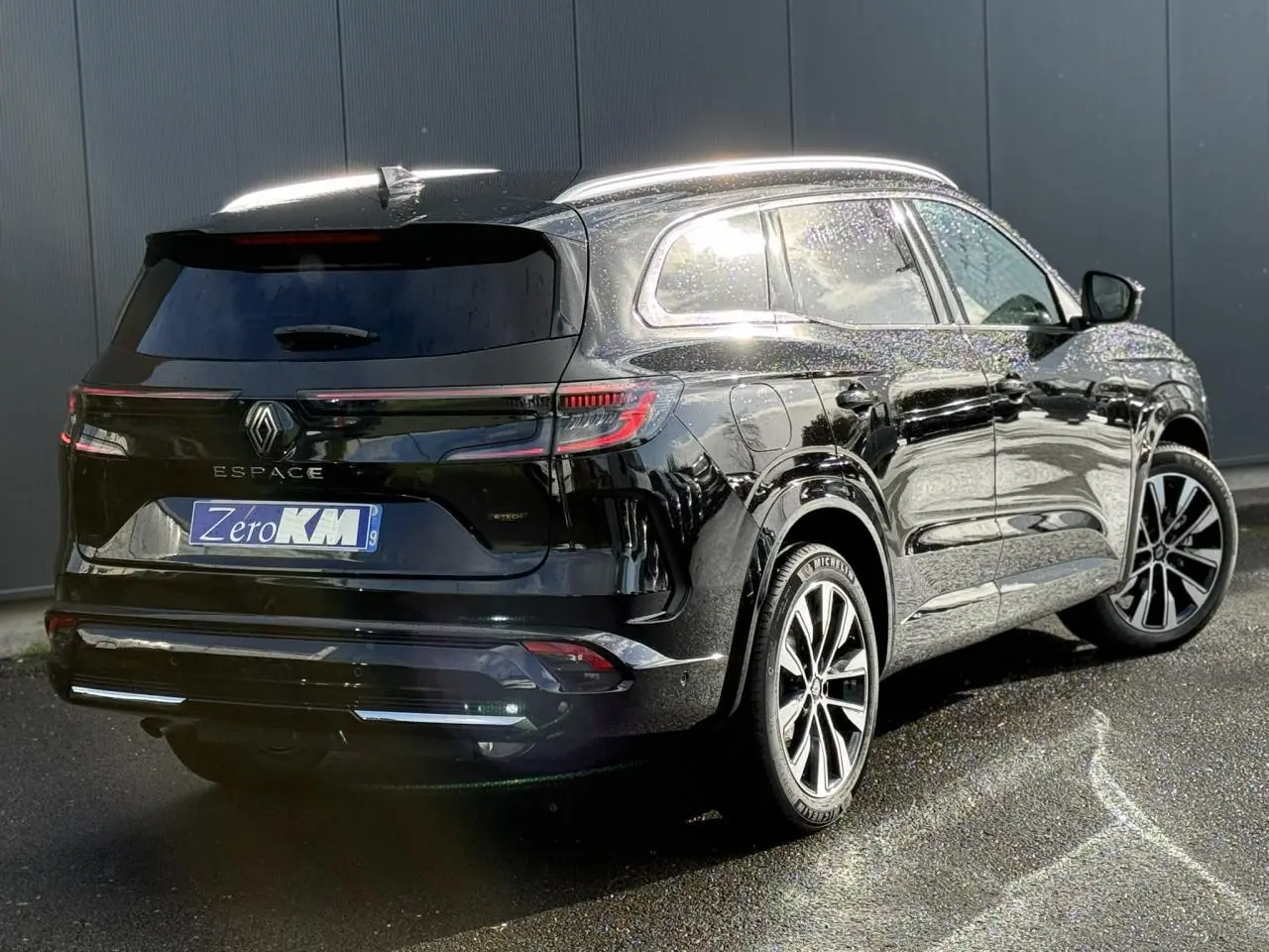 Renault Espace VI noir étoilé vu en 3/4 arrière droit, avec toit panoramique et jantes alliage 19 pouces.