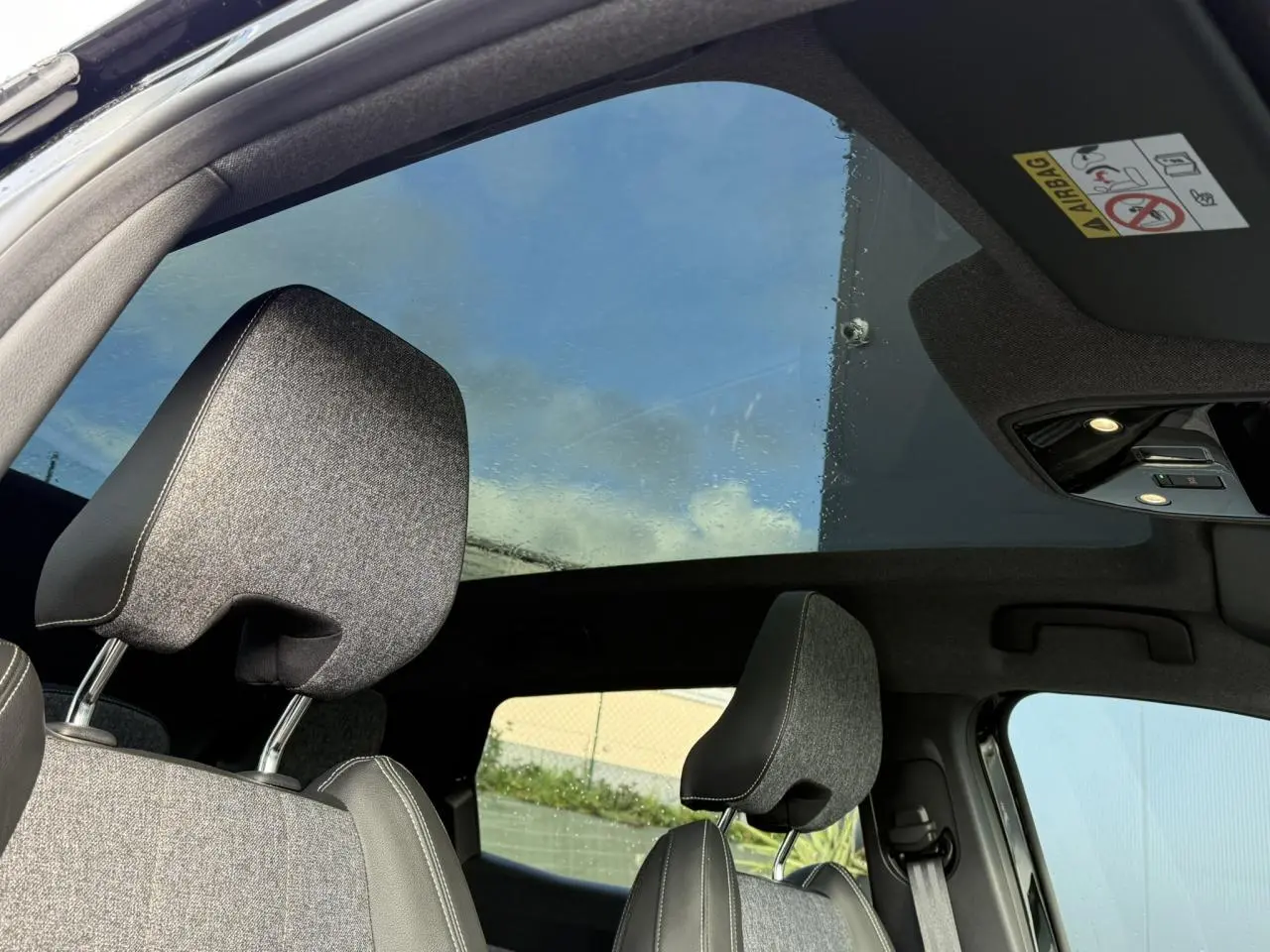 Vue intérieure du toit panoramique en verre du Renault Espace VI avec appuie-têtes gris et ciel visible à travers.