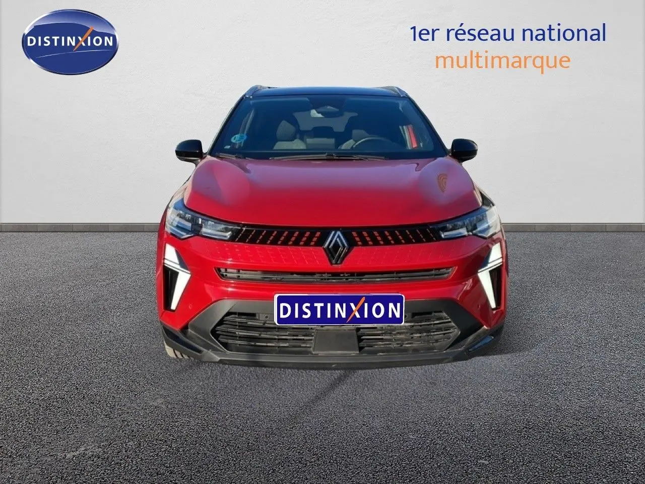 Vue de face du Renault Captur 2025 rouge désir métal avec toit noir, mettant en valeur sa calandre et ses feux LED distinctifs.
