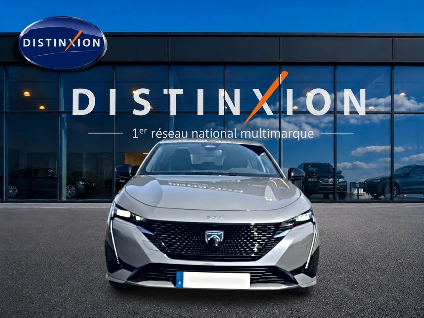 Vue de face d'une Peugeot 308 gris métallisé garée devant une vitrine avec logo Distinxion.
