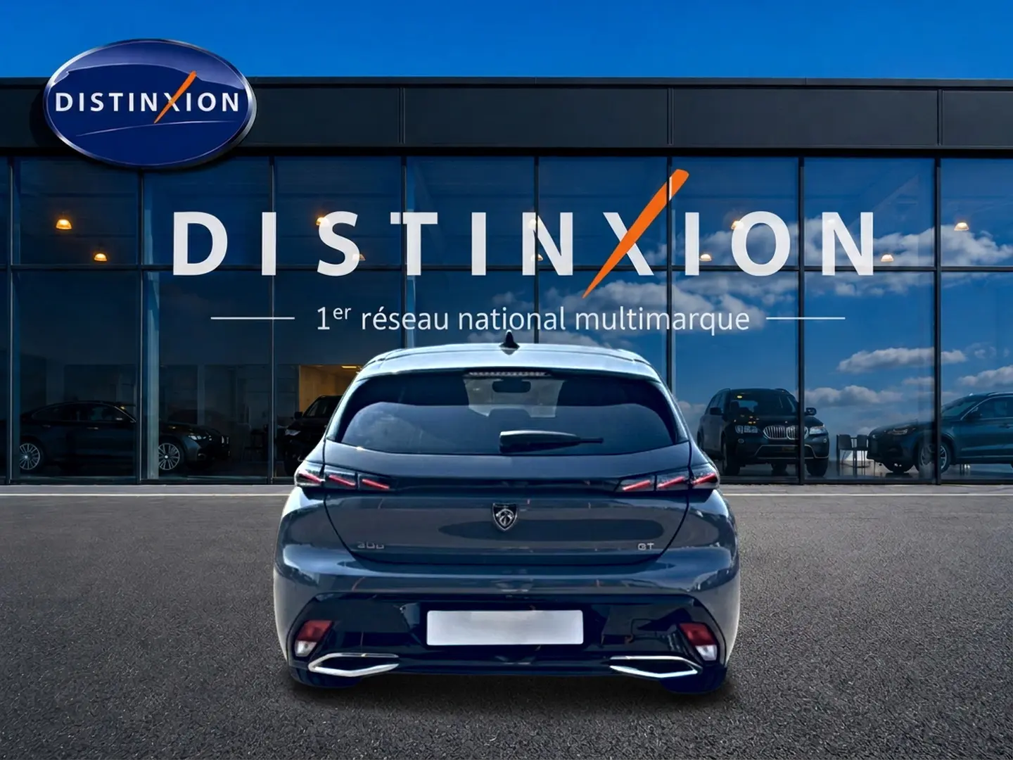 Vue arrière d'une Peugeot 308 gris métallisé garée devant une vitrine avec logo Distinxion.