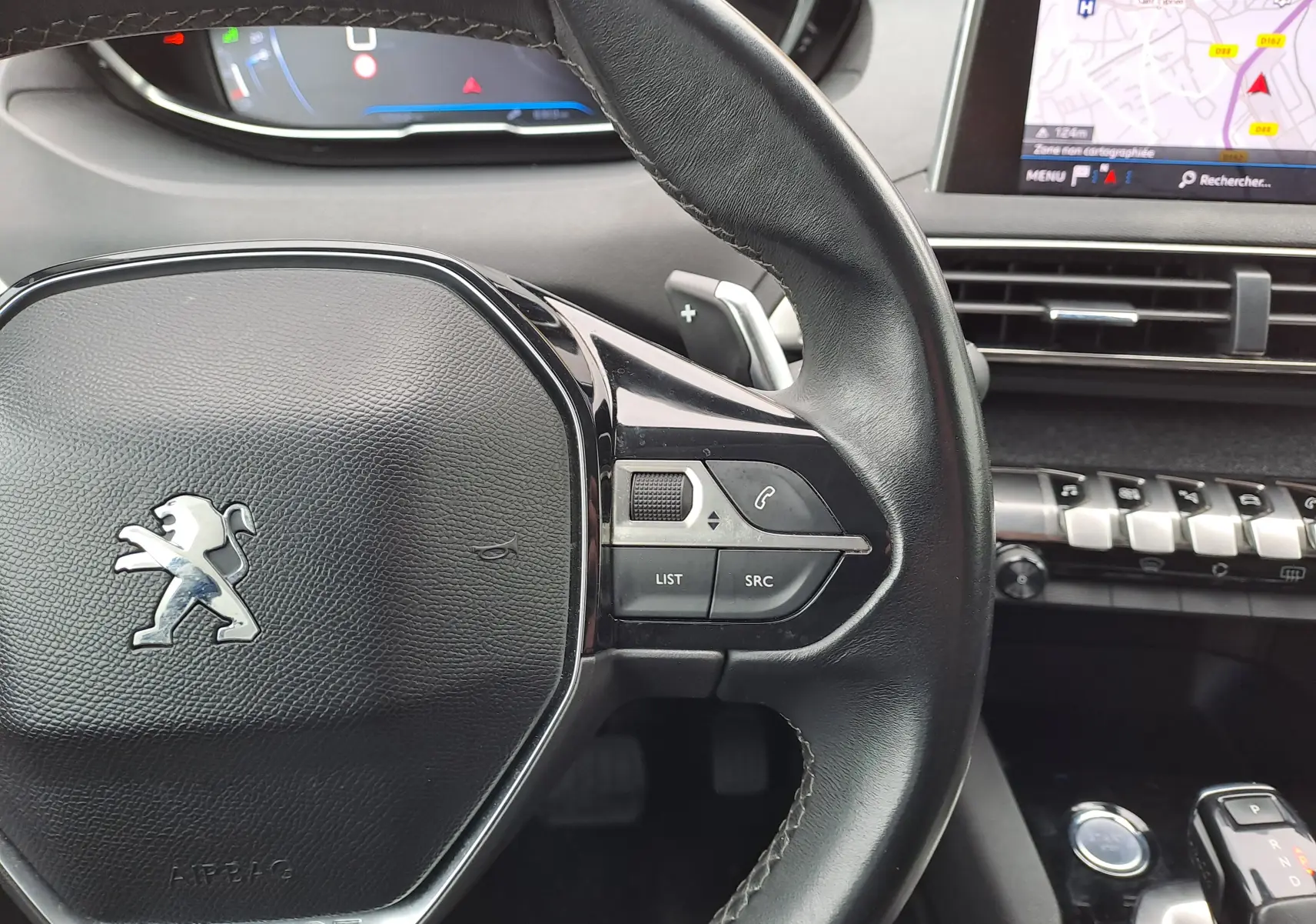 Gros plan sur le volant cuir noir du Peugeot 3008 2018 avec commandes intégrées et écran GPS en arrière-plan.