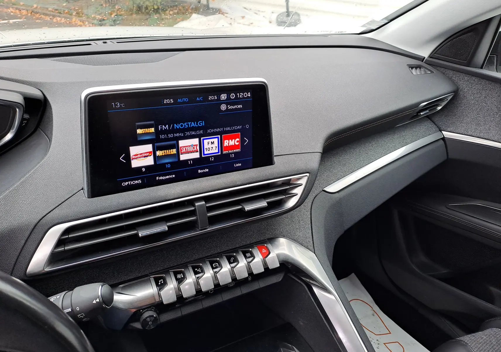 Vue intérieure côté passager du tableau de bord gris du Peugeot 3008 blanc avec écran tactile et commandes piano.