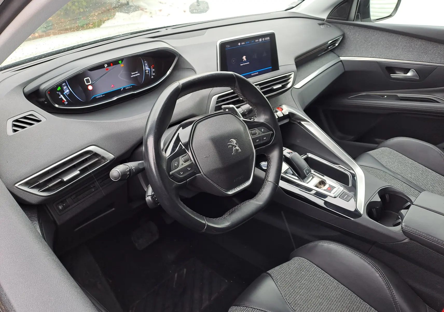 Vue intérieure côté conducteur du Peugeot 3008 blanc 2018, tableau de bord digital et volant compact multifonctions en cuir.