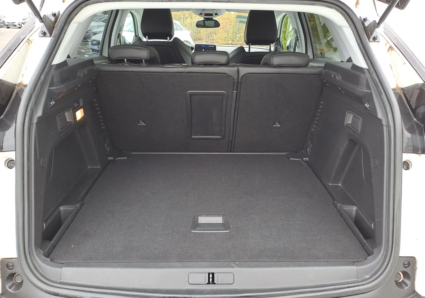 Coffre ouvert vu de l'arrière d'un Peugeot 3008 blanc, montrant un espace de chargement propre et spacieux.