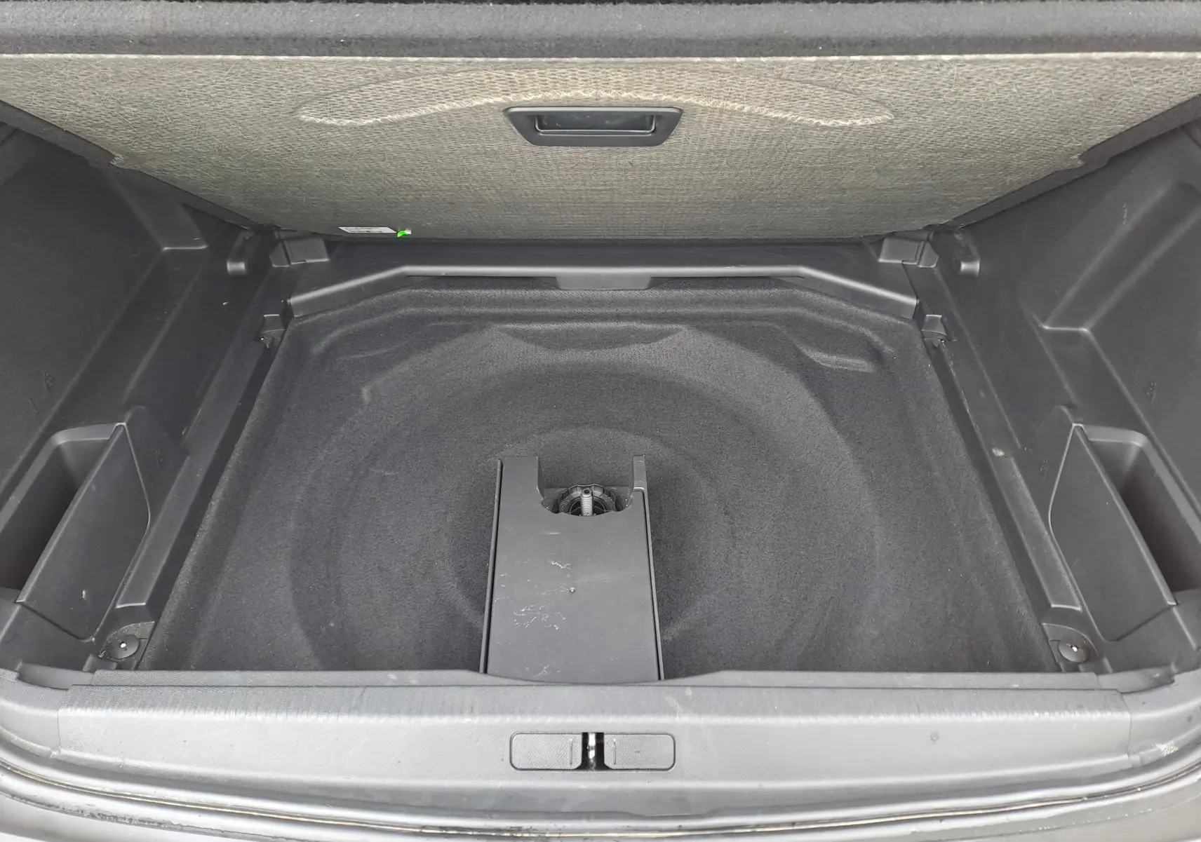 Coffre ouvert du Peugeot 3008 blanc, vue plongeante sur le compartiment de rangement sous plancher.