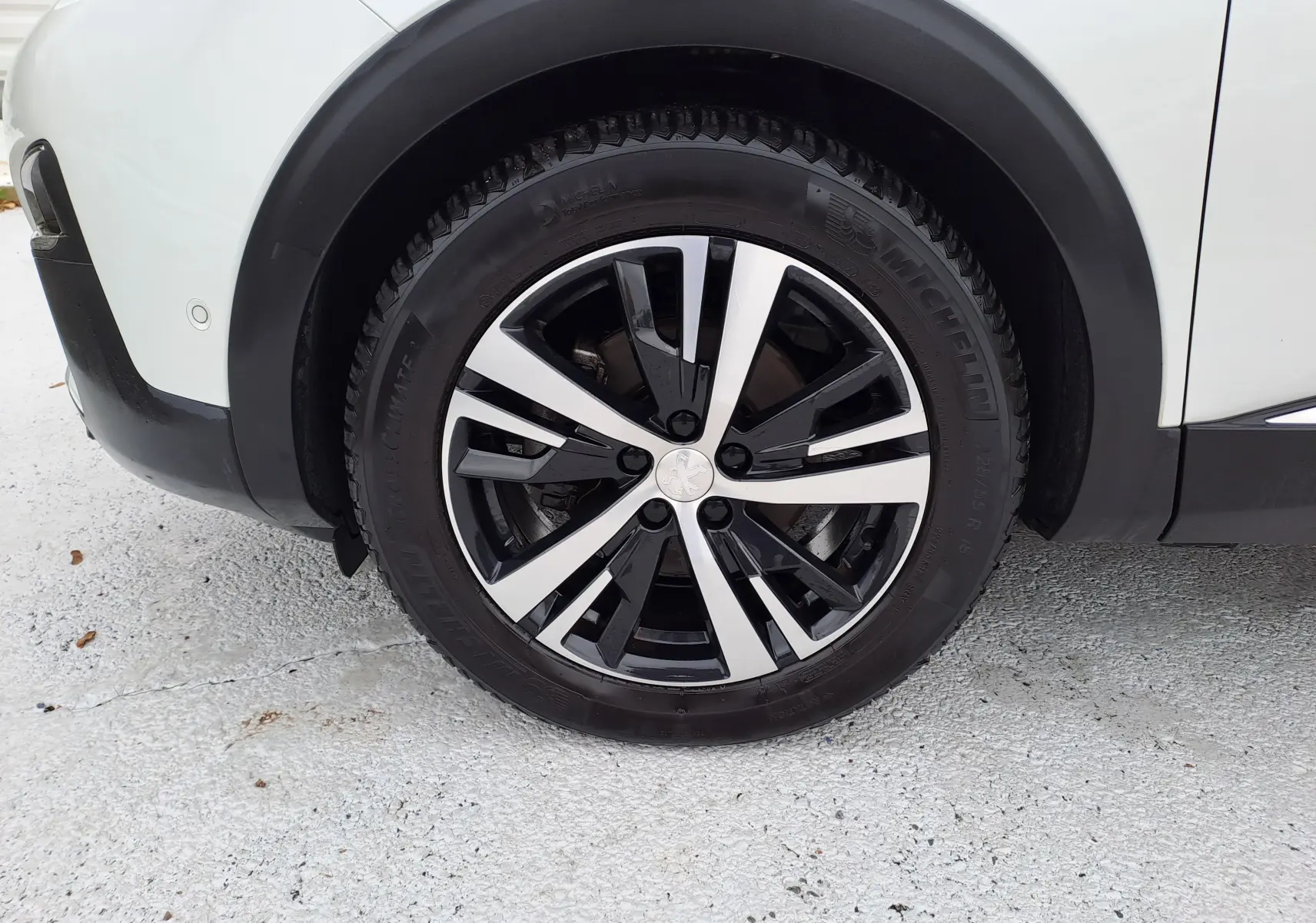 Gros plan sur la roue avant gauche du Peugeot 3008 blanc, mettant en valeur la jante alliage bicolore et le pneu Michelin.