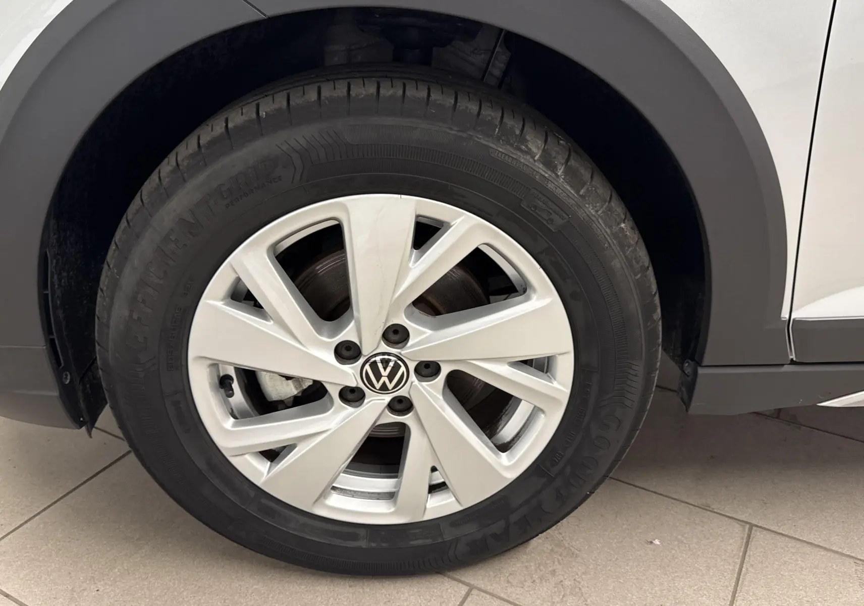 Gros plan sur la roue avant gauche du Volkswagen Taigo gris cendré, mettant en valeur la jante alliage et le logo VW central.