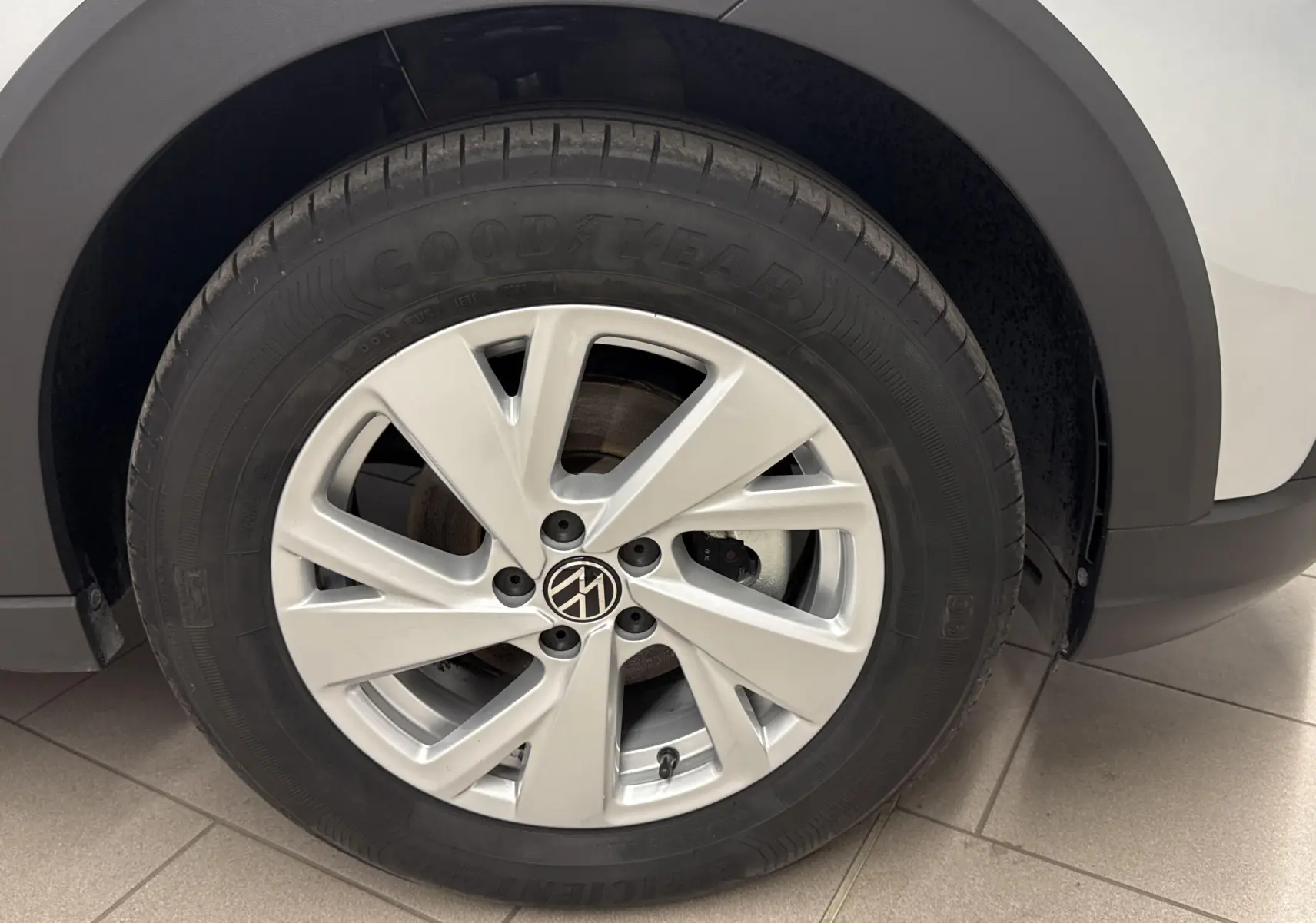 Gros plan sur la roue avant droite d'un Volkswagen Taigo gris cendré avec jante alliage à cinq branches.