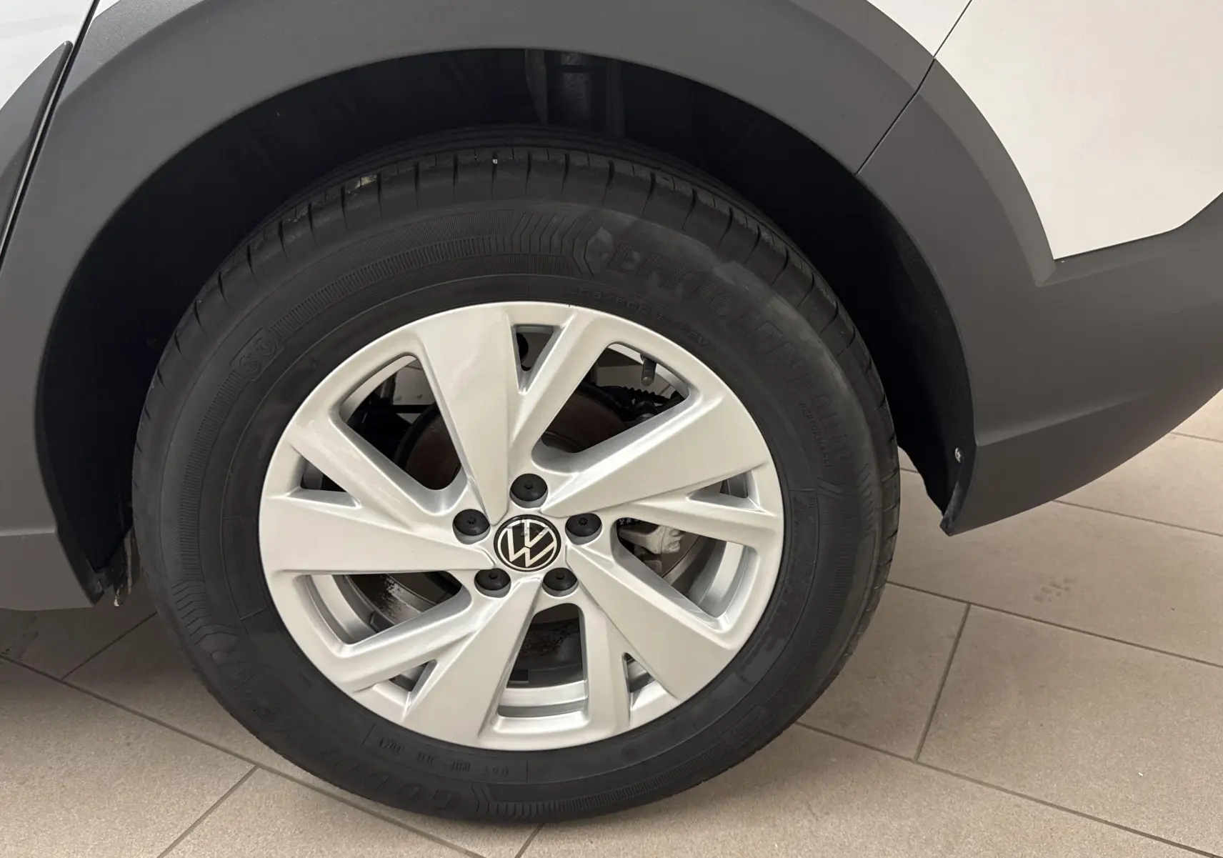 Gros plan sur la roue arrière droite du Volkswagen Taigo gris cendré, mettant en valeur la jante alliage et le logo VW central.