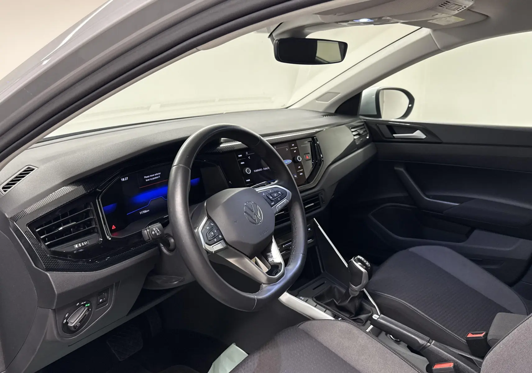 Intérieur avant droit du Volkswagen Taigo gris cendré 2024, tableau de bord moderne avec écran tactile et volant multifonction.