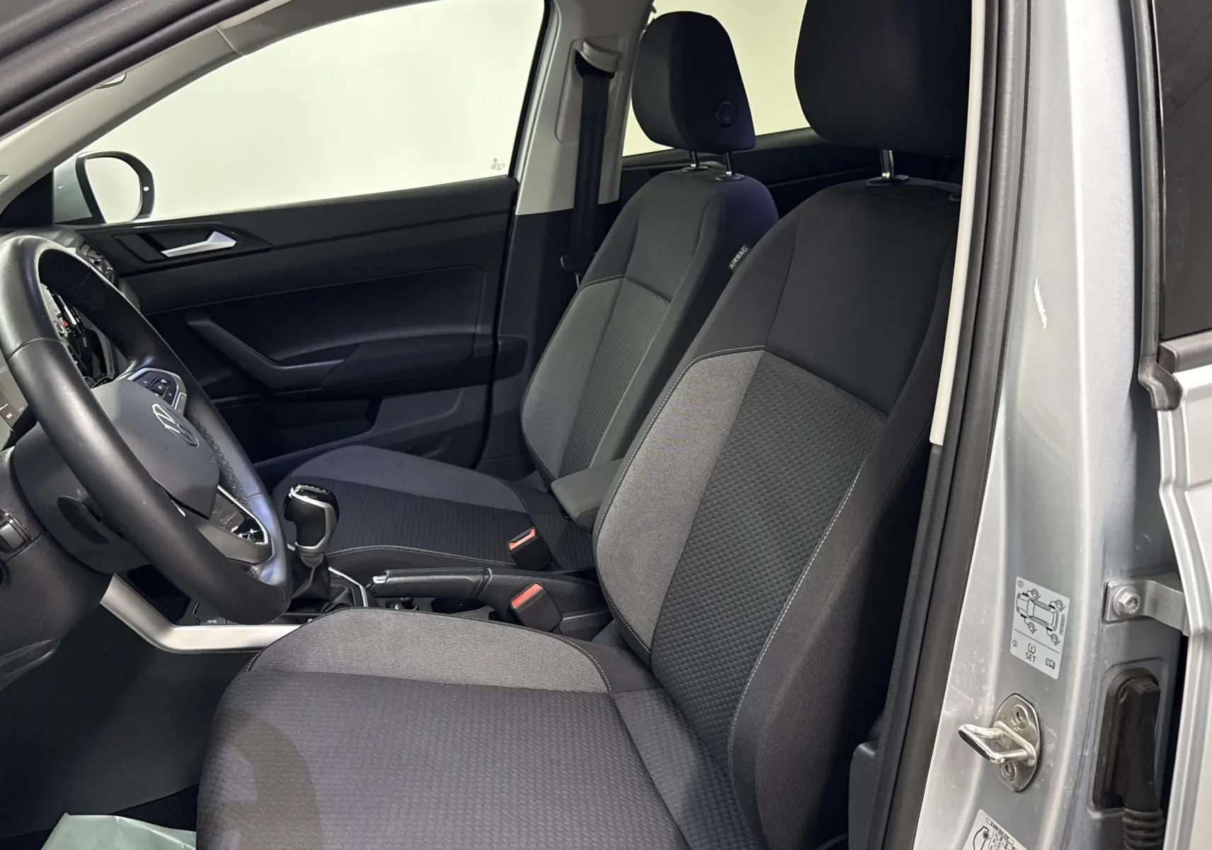 Vue intérieure côté conducteur du Volkswagen Taigo 2024 gris cendré, montrant les sièges avant et le volant.