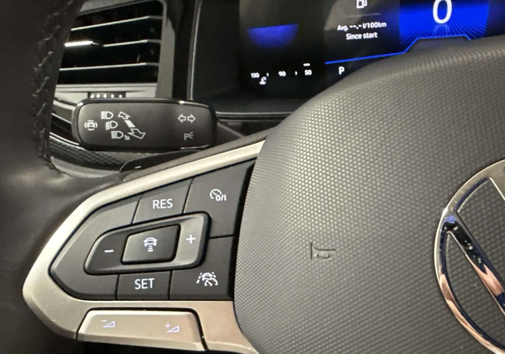 Gros plan sur le volant du Volkswagen Taigo 2024 avec commandes intégrées et tableau de bord numérique en arrière-plan.