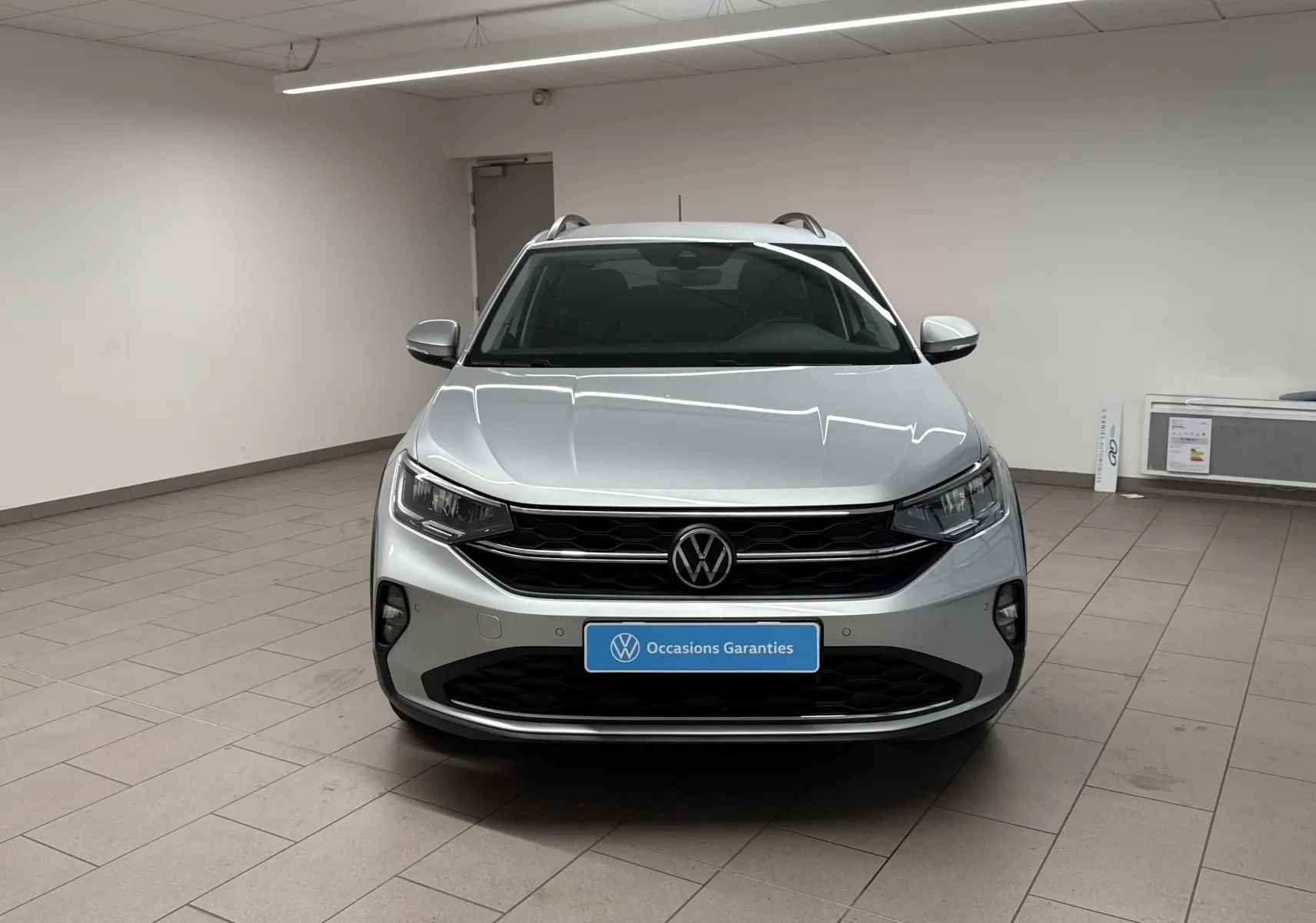 Volkswagen Taigo gris cendré vu de face dans un showroom, mettant en valeur sa calandre noire et ses phares LED.