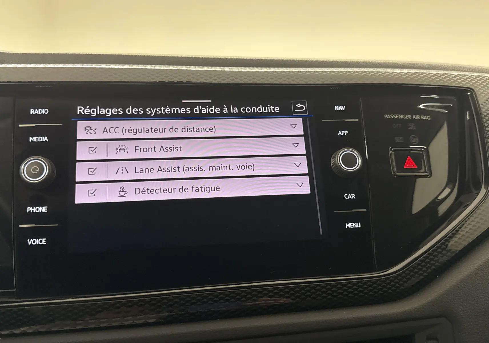 Écran tactile central du Volkswagen Taigo 2024 affichant les réglages des aides à la conduite avec finition intérieure noire.