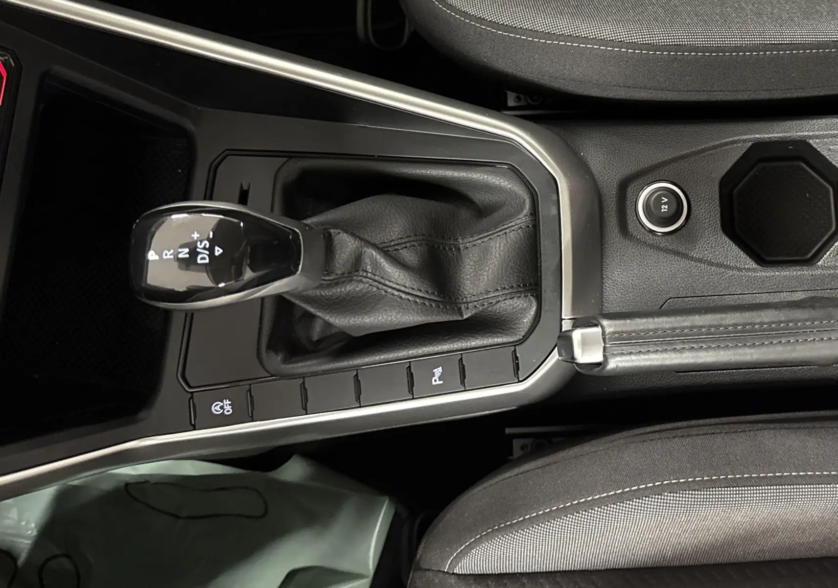 Vue plongeante sur la console centrale du Volkswagen Taigo 2024 avec levier de vitesse automatique et frein à main cuir noir.