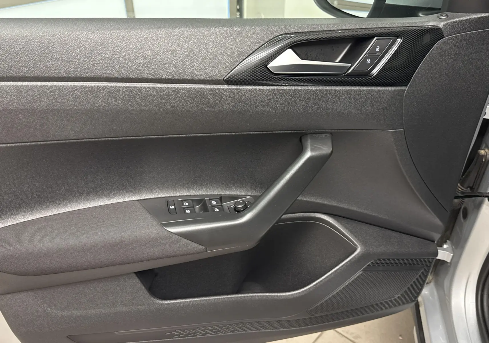 Vue rapprochée de la porte avant gauche du Volkswagen Taigo gris cendré avec commandes de vitres et verrouillage.