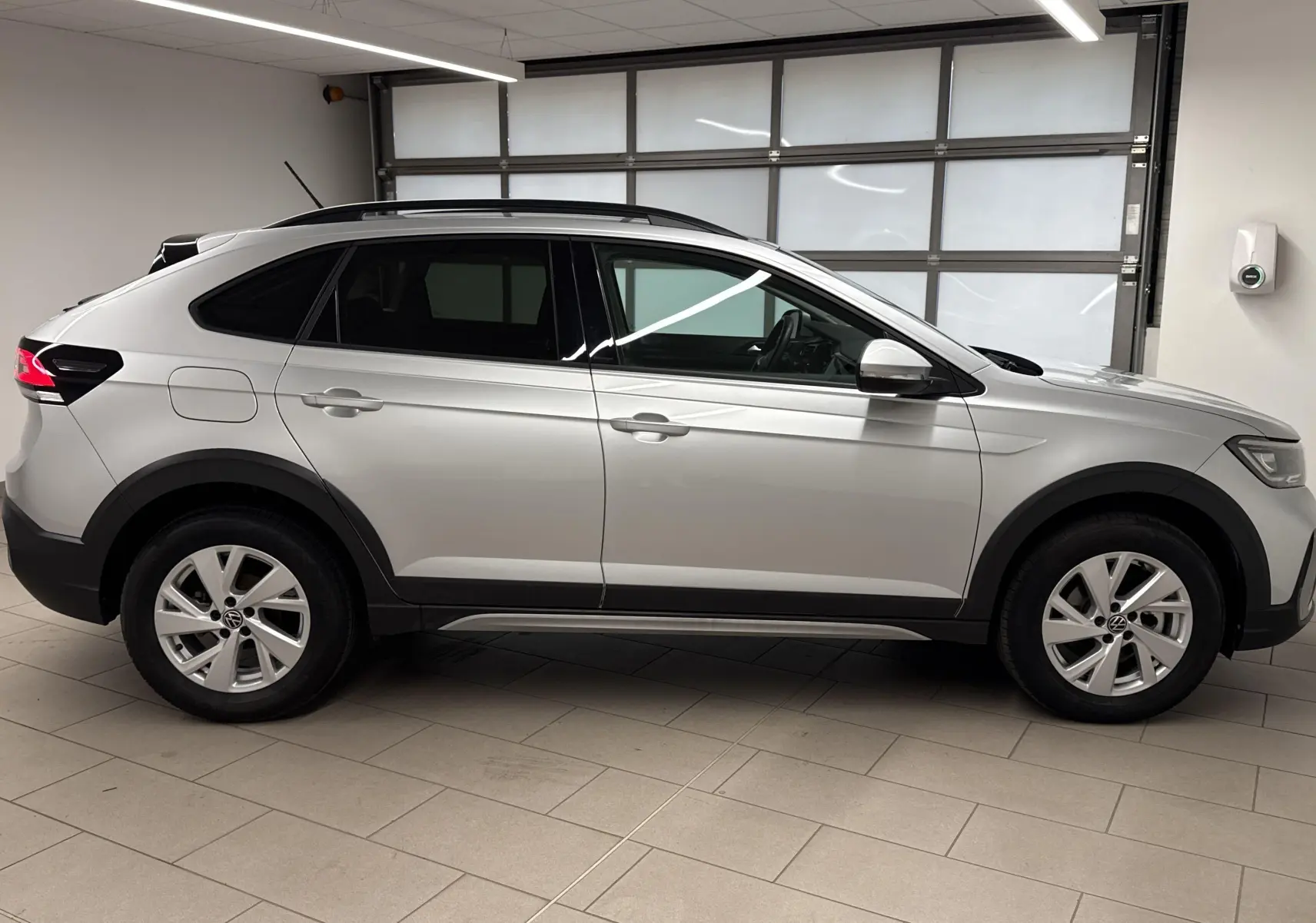 Profil droit d'un Volkswagen Taigo 1.0 TSI 110 DSG7 Life gris cendré métallisé en intérieur lumineux.