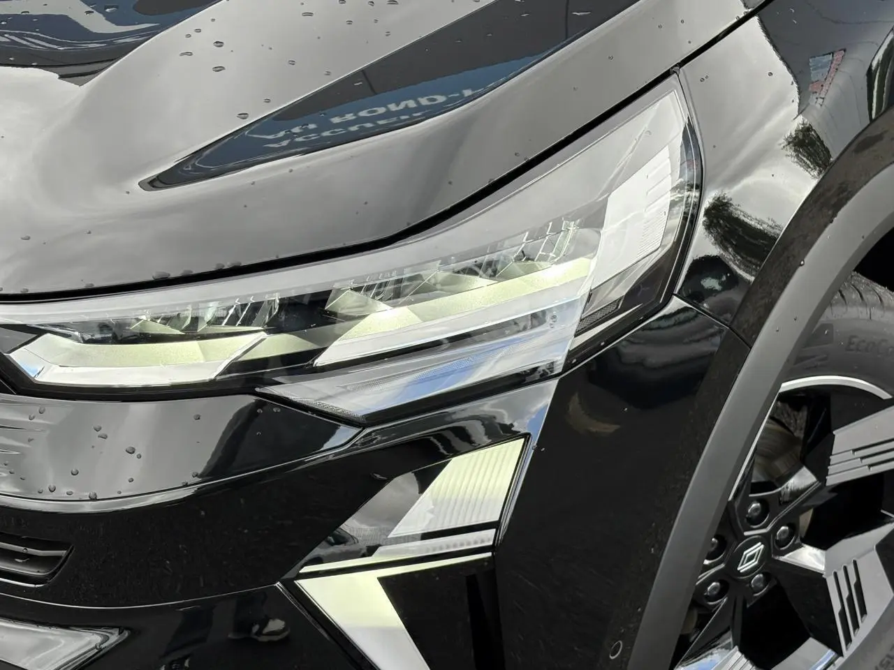 Gros plan sur le phare avant gauche et la jante 18" Gravity du Renault Symbioz noir étoile 2025.