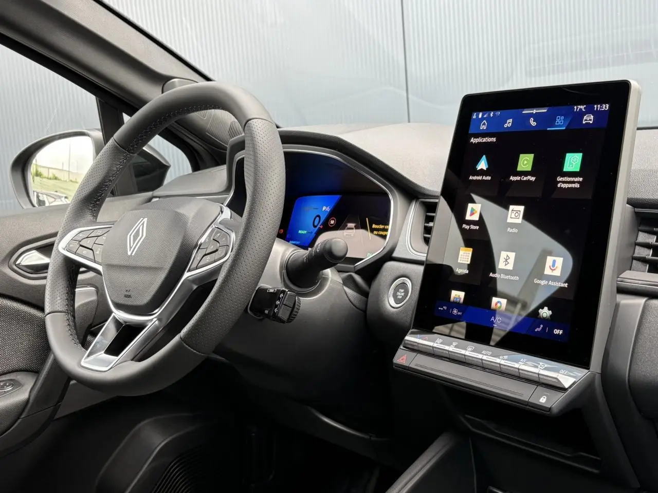 Vue intérieure côté conducteur du Renault Symbioz 2025, volant cuir et grand écran tactile vertical noir.