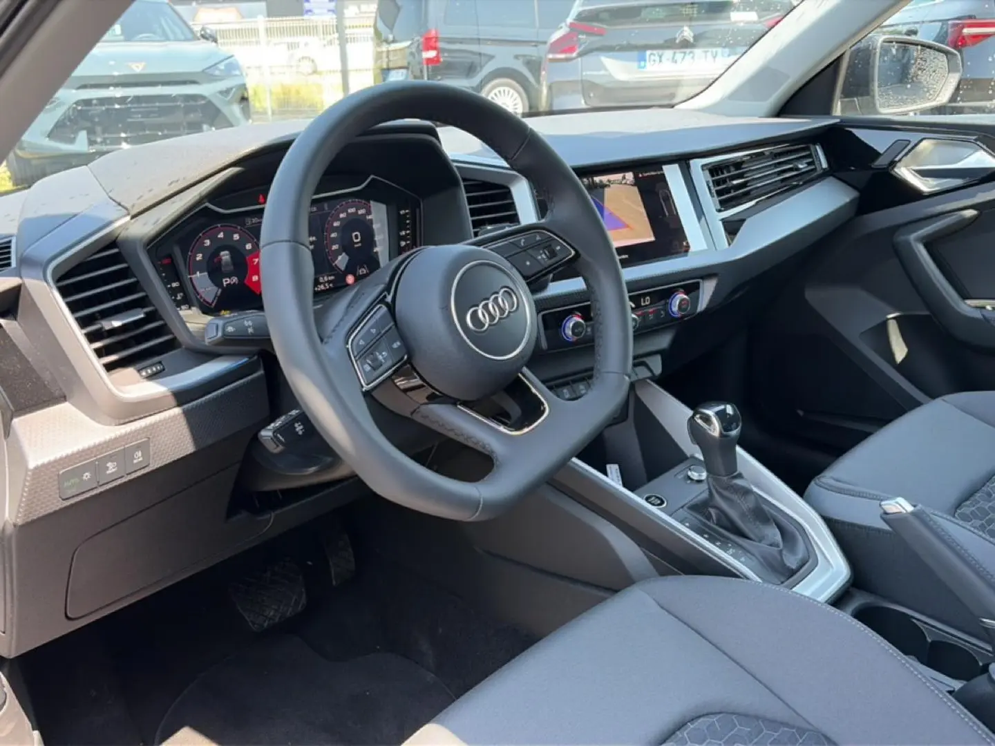 Vue intérieure côté conducteur de l'Audi A1 Sportback 2026 avec volant cuir multifonction et tableau de bord digital.