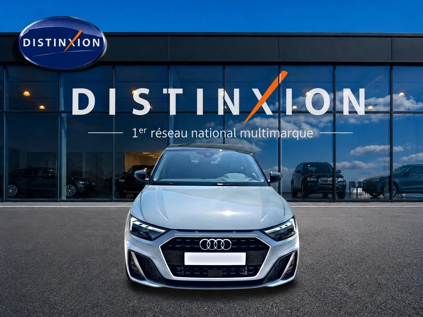 Audi A1 Sportback gris arrow vue de face, avec calandre noire et logo Audi bien visible devant un showroom Distinxion.