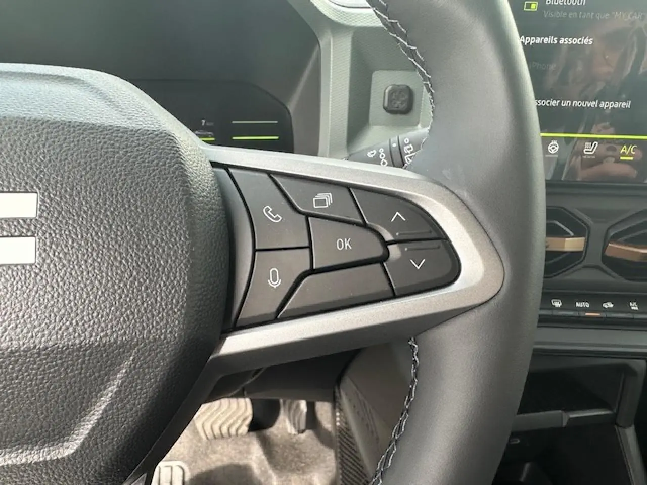 Gros plan sur les commandes au volant à droite du Dacia Duster III gris schiste, avec écran tactile et tableau de bord partiel visible.