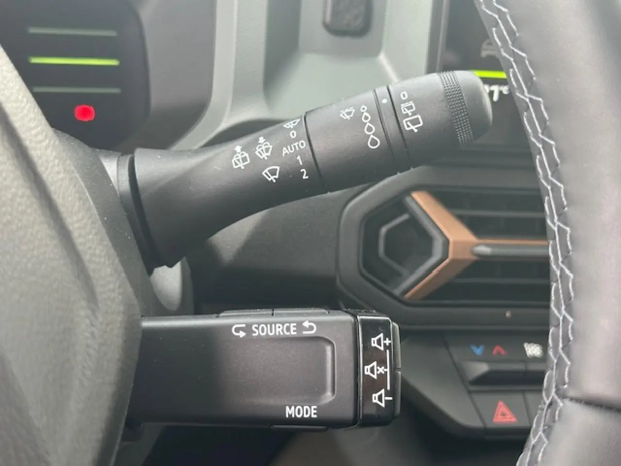 Gros plan sur les commandes au volant du Dacia Duster gris schiste, avec détails des commandes d'essuie-glace et multimédia.
