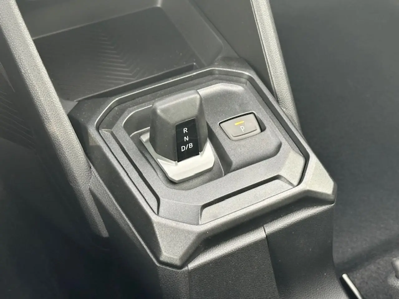 Le levier de vitesses automatique et bouton de parking du Dacia Duster III 1.6 Hybrid 140 en intérieur noir.