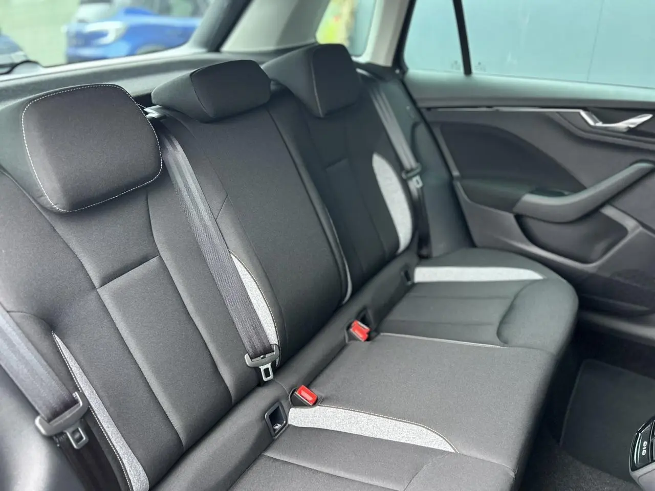 Vue intérieure du siège arrière droit du Skoda Kamiq 2025 noir Magic avec tissu gris clair et ceintures visibles.