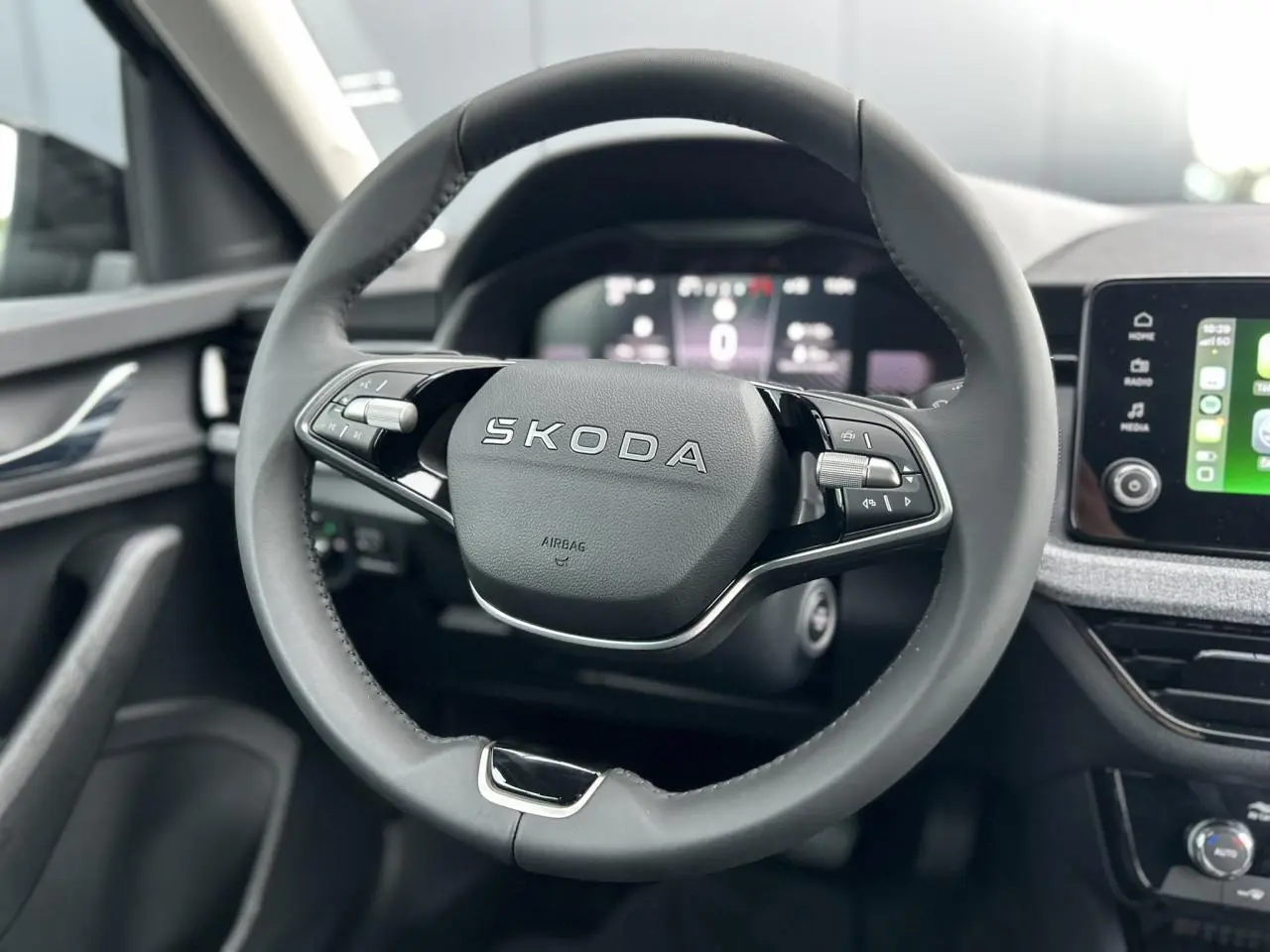 Vue rapprochée du volant cuir multifonctions SKODA KAMIQ 2025 avec tableau de bord digital et écran tactile visible.