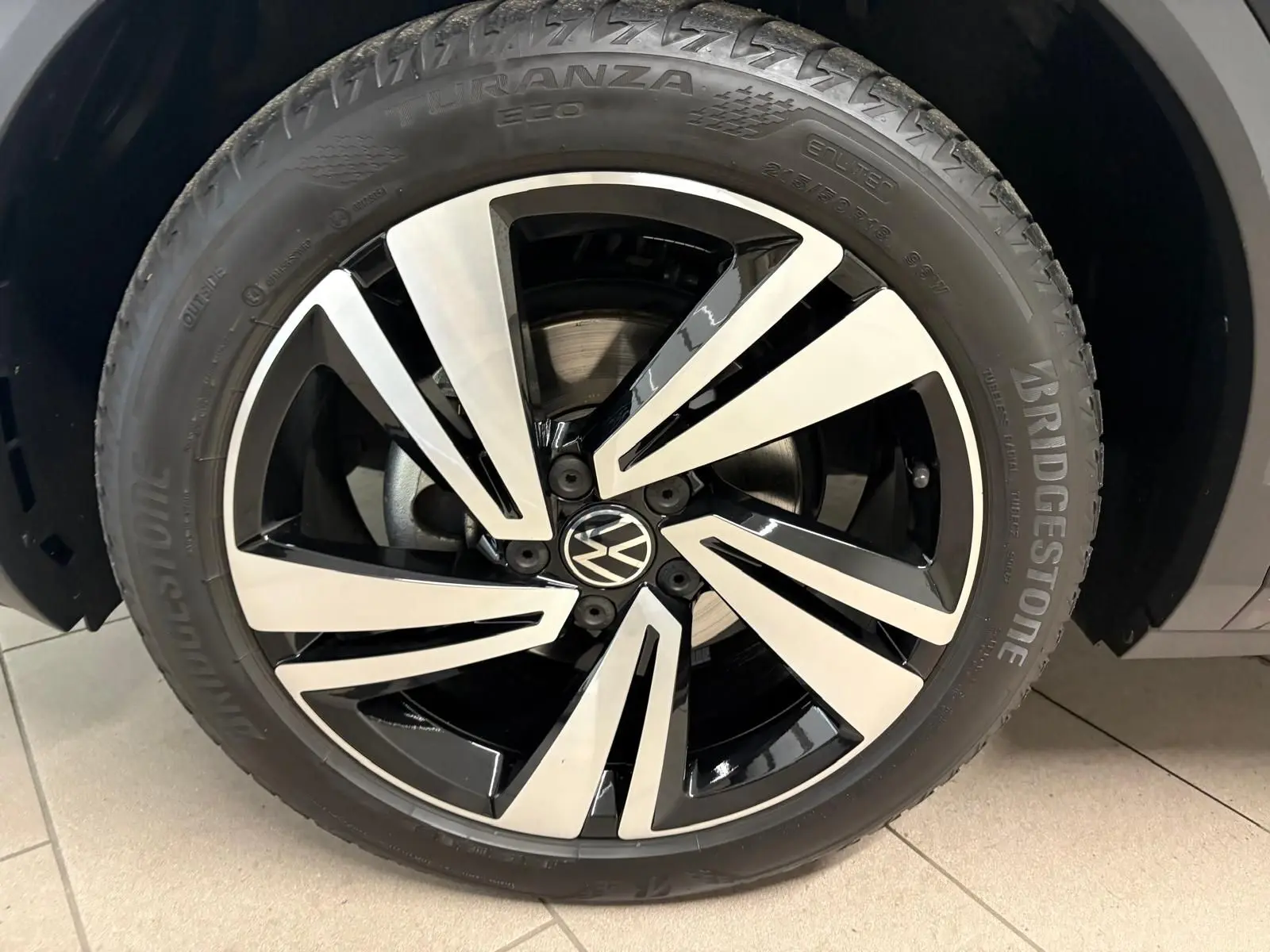 Gros plan sur la jante alliage bicolore noir et argent du Volkswagen T-Roc 1.5 TSI 150 DSG7 R-Line Edition noir intense.