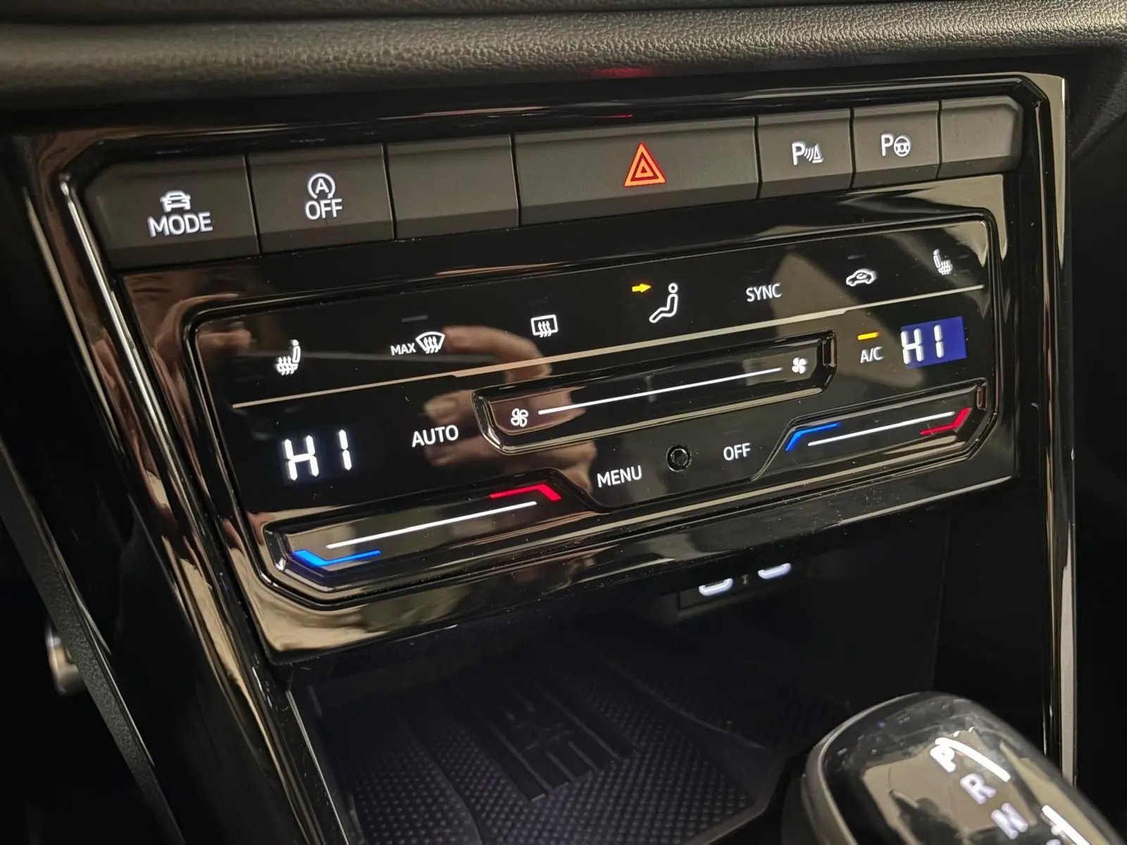 Gros plan sur la console centrale noire du Volkswagen T-Roc 2025, affichant la climatisation automatique et la boîte auto DSG7.