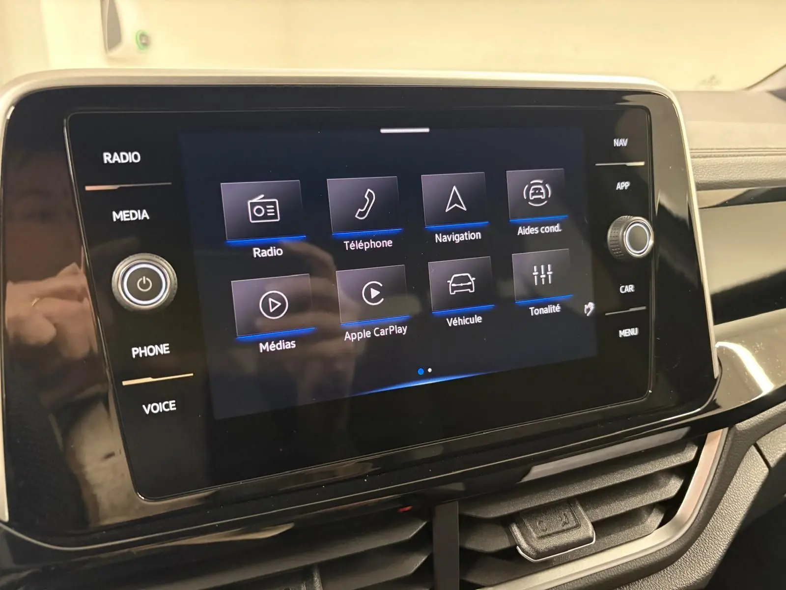 Écran tactile central du Volkswagen T-Roc 2025 affichant les options radio, téléphone, navigation et aides à la conduite.