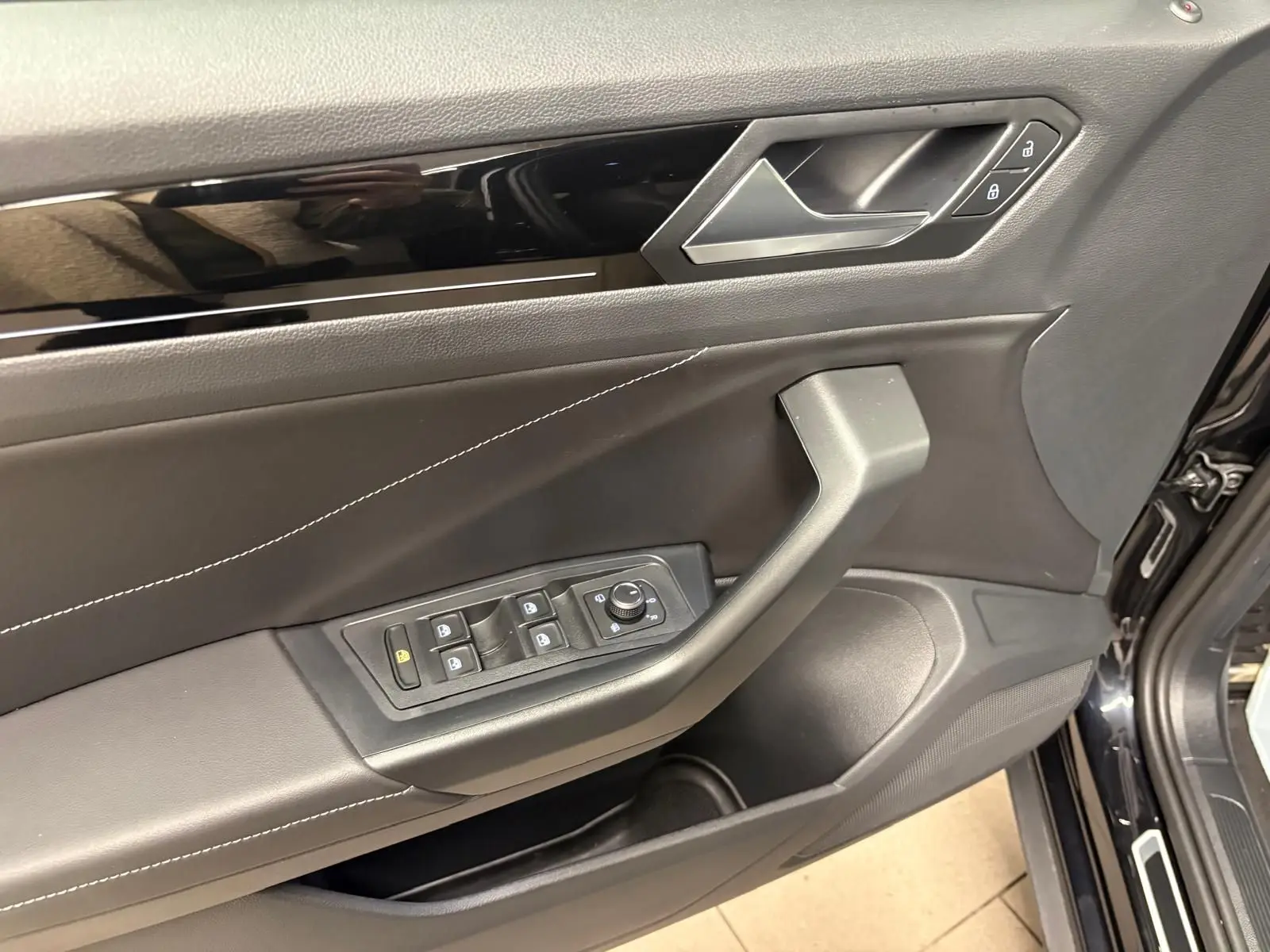 Gros plan sur la porte avant gauche noire du Volkswagen T-Roc 1.5 TSI R-Line avec commandes de vitres et verrouillage.