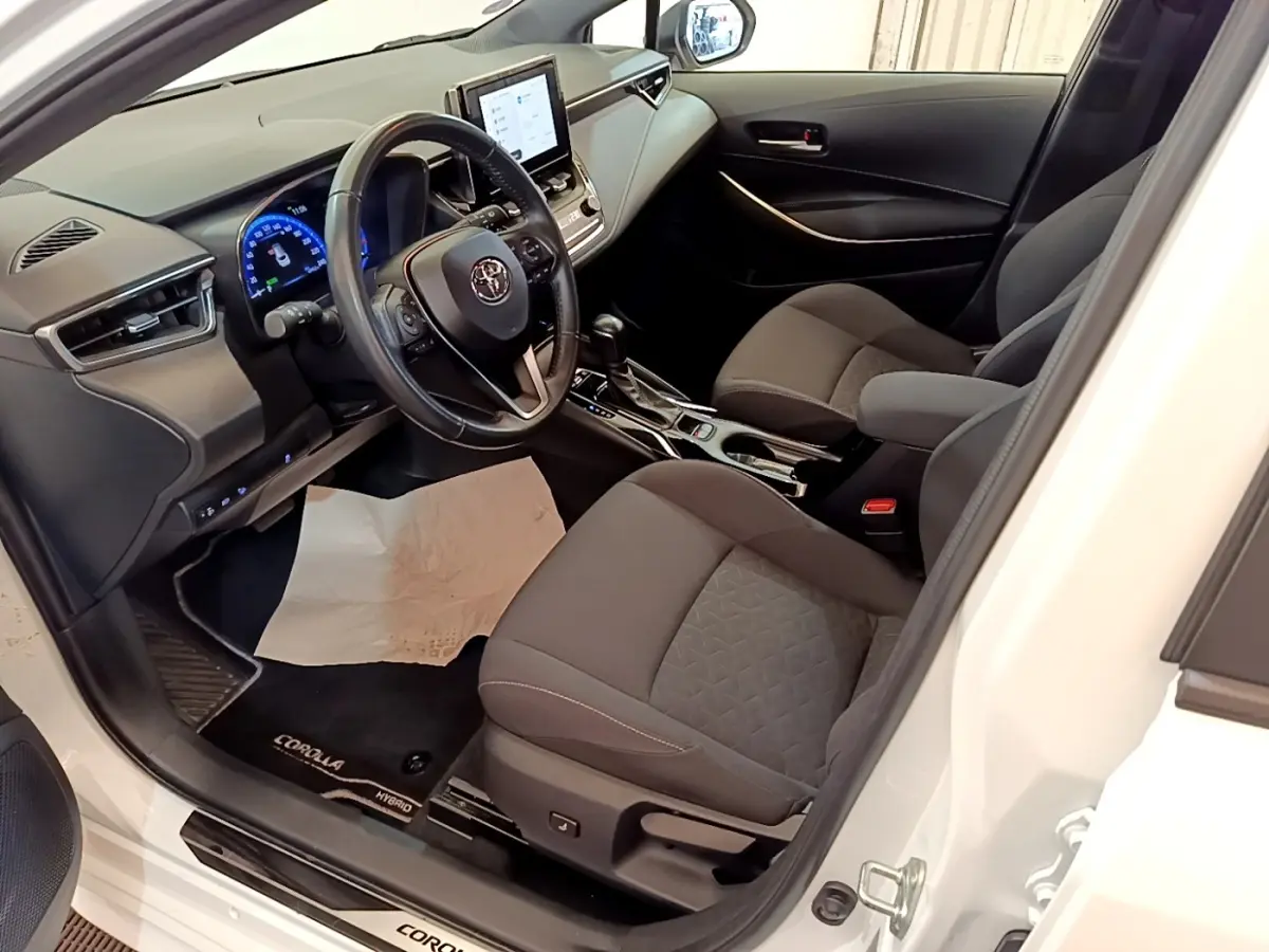 Intérieur avant droit de Toyota Corolla hybride blanche 2022, avec tableau de bord numérique et écran tactile central.