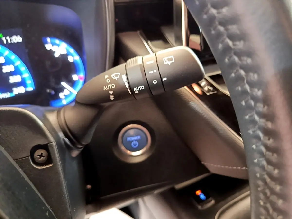 Gros plan intérieur sur le commodo d’essuie-glace et bouton start/stop bleu de la Toyota Corolla hybride 2022.