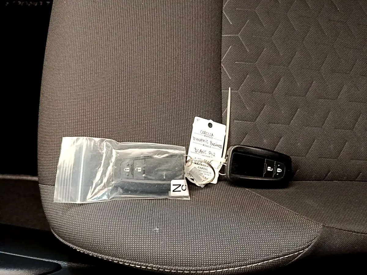 Gros plan sur la banquette arrière grise avec deux clés noires de Toyota Corolla hybride posées dessus.