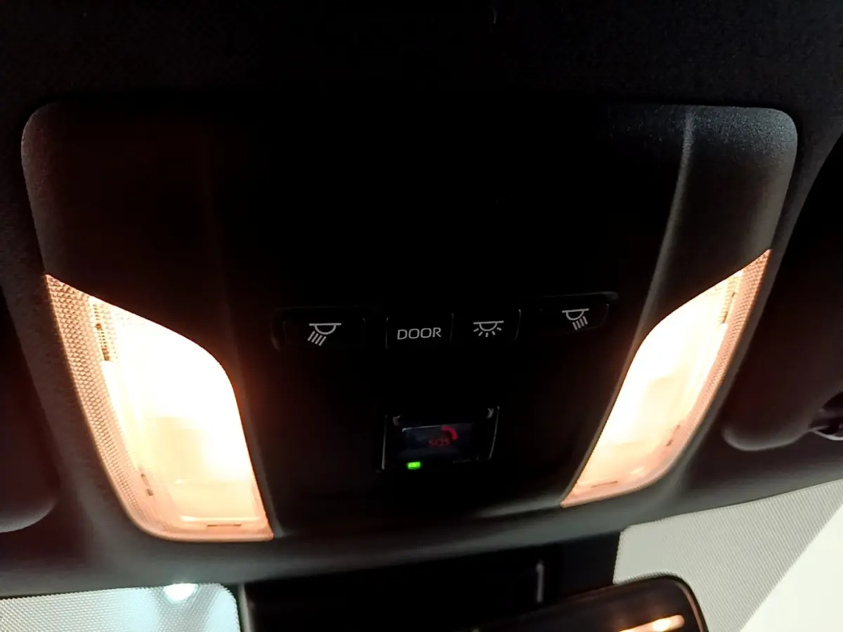 Plafonnier intérieur allumé avec commandes d’éclairage et bouton SOS dans une Toyota Corolla hybride blanche 2022.