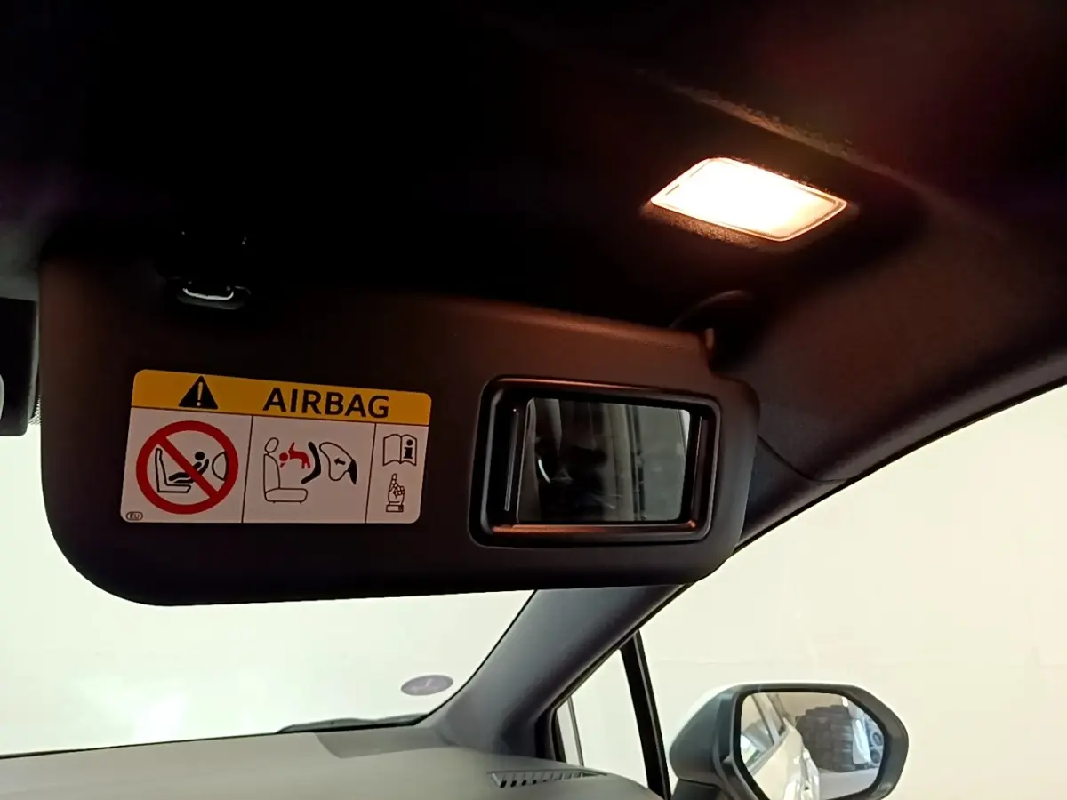 Intérieur de la Toyota Corolla hybride 2022, vue côté conducteur sur pare-soleil avec miroir et avertissement airbag.