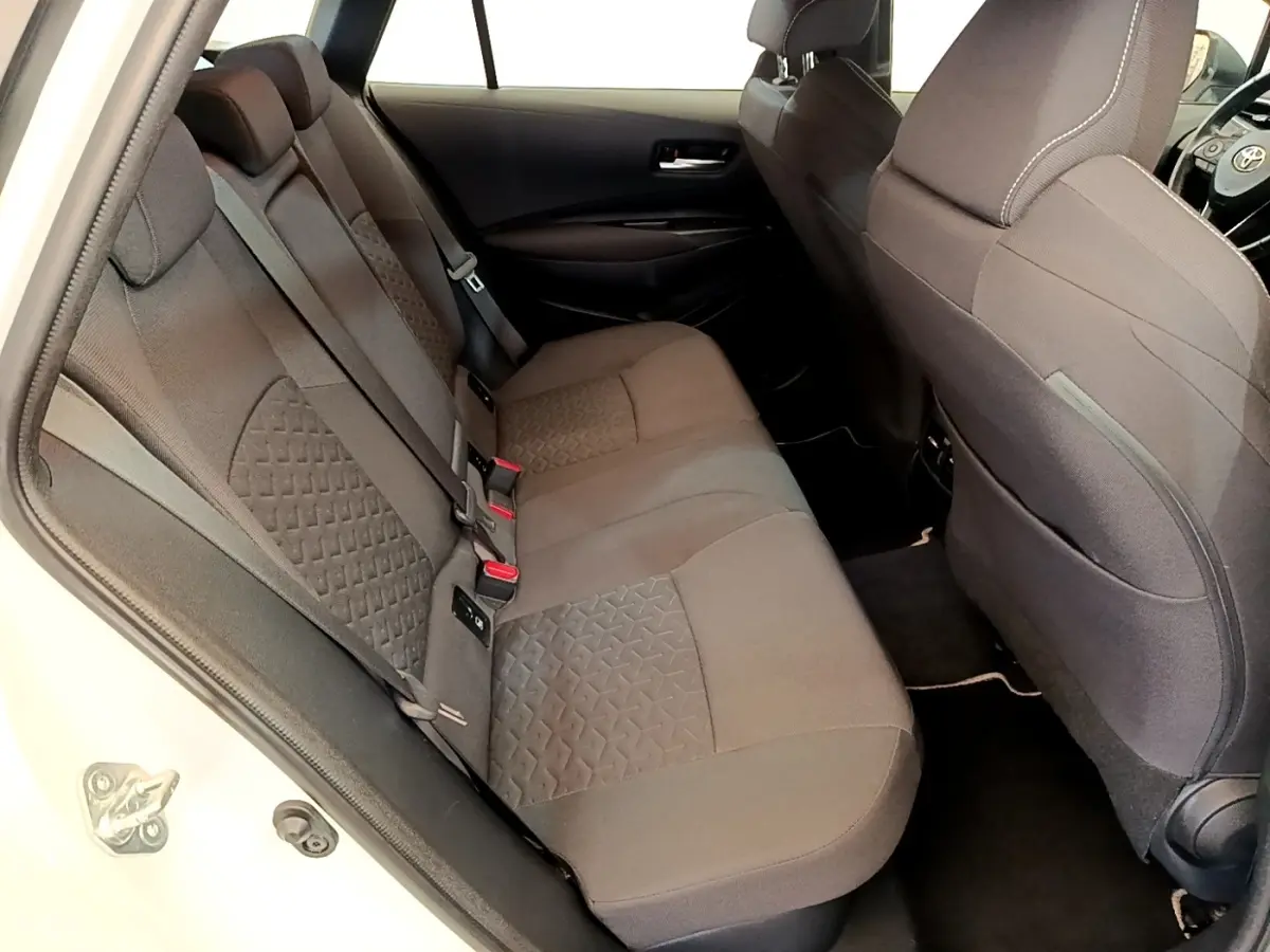 Vue intérieure côté gauche montrant la banquette arrière grise de la Toyota Corolla Hybride 2022 blanche.