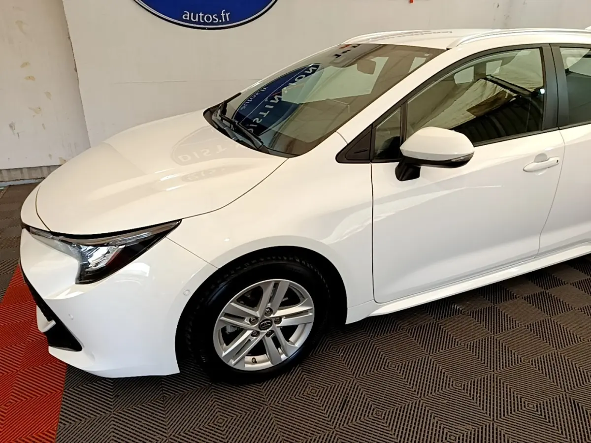 Vue 3/4 avant droite d'une Toyota Corolla hybride blanche avec jantes alliage et rétroviseurs blancs.