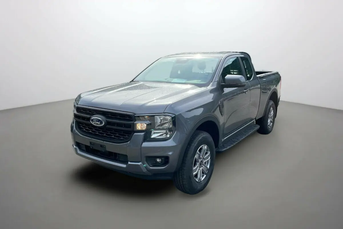 Ford Ranger gris carbone en 3/4 avant droit, avec marchepieds latéraux et calandre noire distinctive.