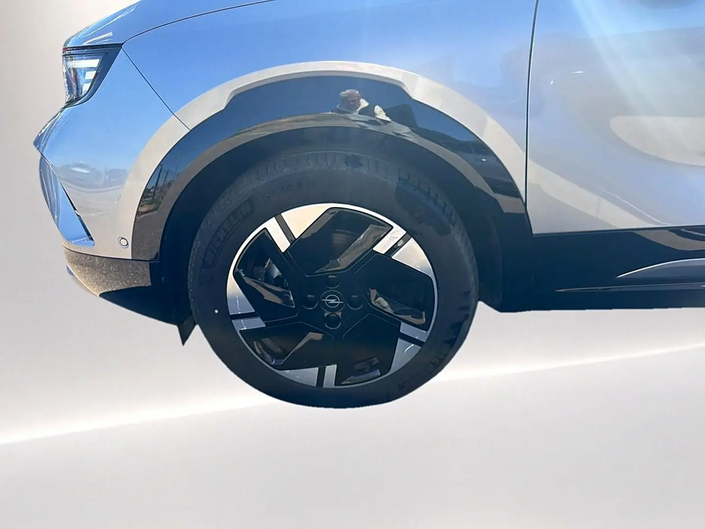 Gros plan sur la roue avant gauche et une partie de la carrosserie gris clair de l'Opel Mokka Electric 2025.