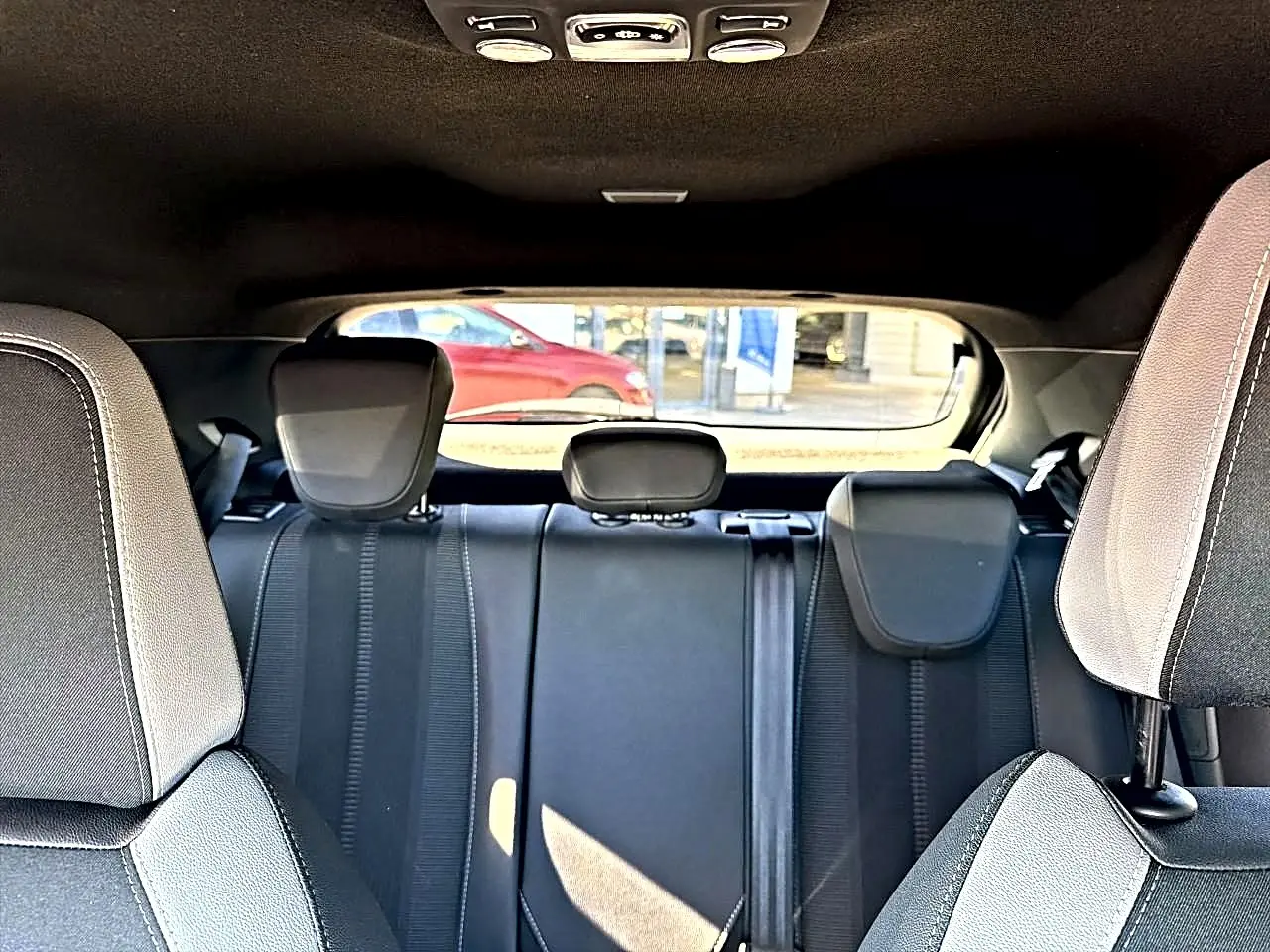 Vue intérieure arrière de l'Opel Mokka Electric 156 GS 2025, sièges gris foncé avec appuie-têtes et ceintures visibles.