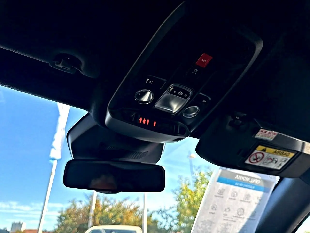 Vue intérieure du toit et rétroviseur d’un Opel Mokka Electric gris, avec commandes d’éclairage et bouton SOS visibles.