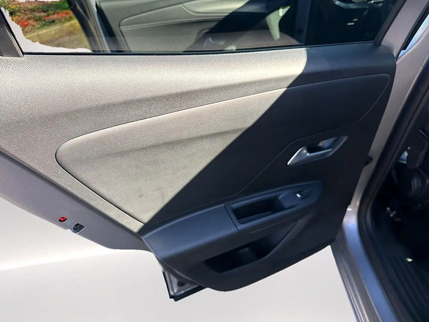 Vue rapprochée de la porte arrière droite grise de l’Opel Mokka Electric 156 gs avec poignée et commande de vitre.