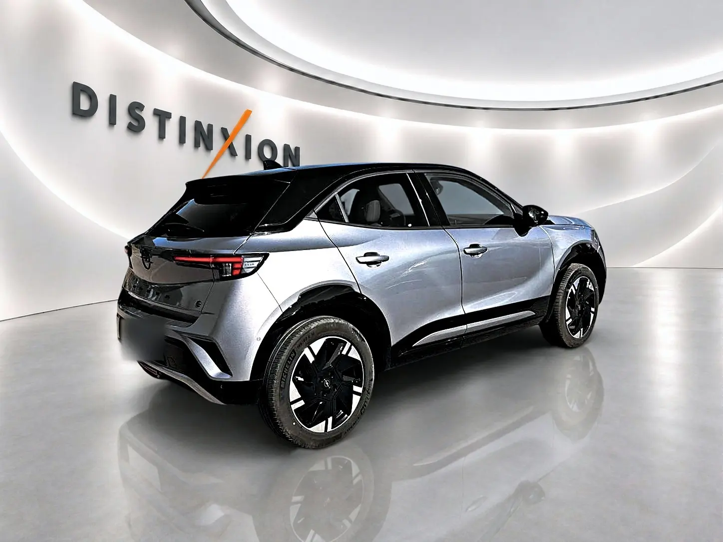 Opel Mokka Electric 156 GS gris 3/4 arrière droit avec toit noir et jantes alu bicolores dans showroom.