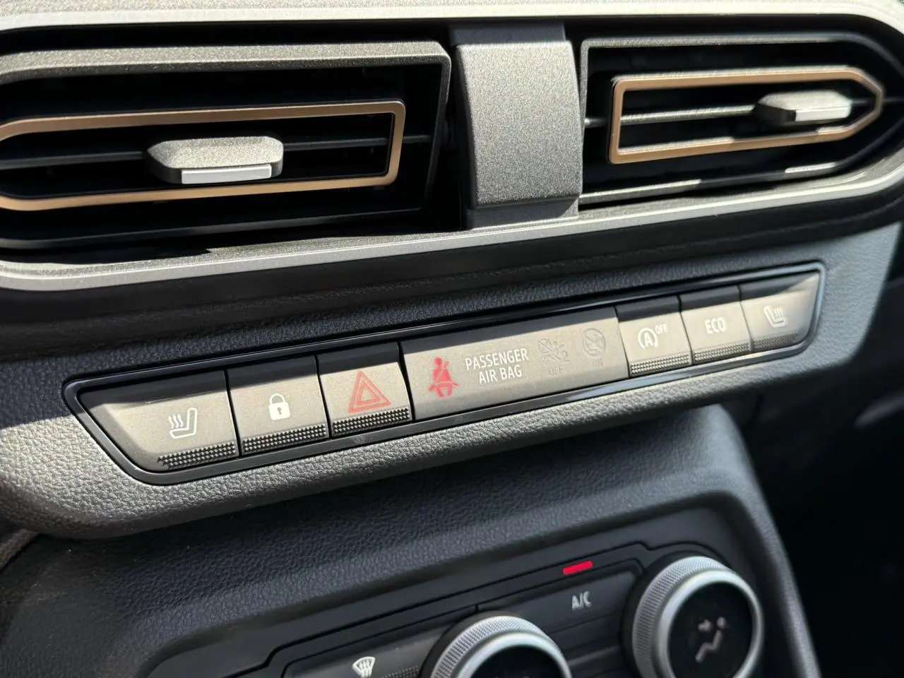 Gros plan sur la console centrale du Dacia Sandero Stepway 2025, boutons de confort et ventilation noire.